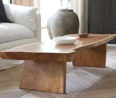 a wooden table sitting on top of a hard wood floor next to a white couch