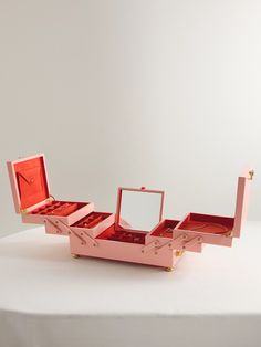 an open pink jewelry box sitting on top of a white table with a mirror in it