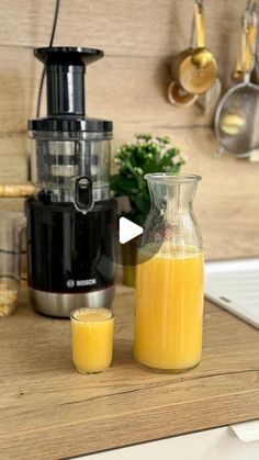 an orange juice in a glass next to a blender