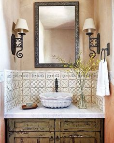 a bathroom sink sitting under a mirror next to a wooden cabinet with drawers and lights