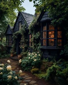 a house that is surrounded by greenery and flowers in the front yard, with a stone path leading up to it