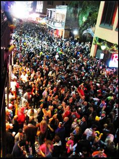 a large group of people standing in the middle of a city street at night time