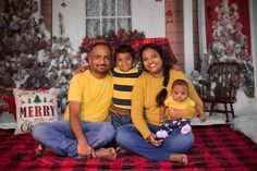 a man and woman sitting on a bed with a baby in front of christmas decorations