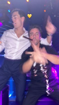 two men are dancing on the dance floor with their hands in the air and one man is holding his mouth open