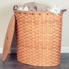 a laundry basket with a wooden lid and two white balls in the bottom, sitting on top of a hard wood floor