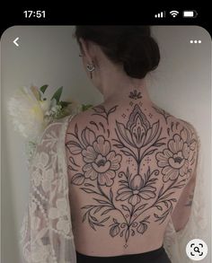 the back of a woman's body with flowers on it and an intricate design