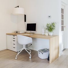 a desk with a computer on top of it next to a lamp and potted plant