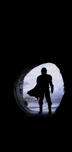 the silhouette of a man in a star wars costume is seen through a dark tunnel