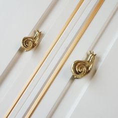 two gold handles on white cabinet doors with wooden dows and brass pulls in the middle