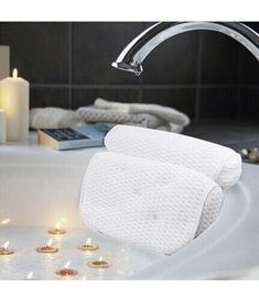 a bathtub filled with lots of candles next to a book and some books on the counter