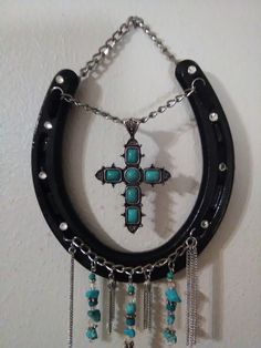 a cross is hanging on the wall with chains and beads attached to it's sides