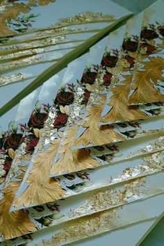 several pieces of paper with gold and red flowers on them are sitting next to each other