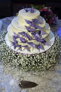 a white cake with purple origami cranes on it