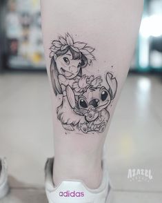 a tattoo on the leg of a woman with an image of disney and stitching