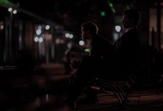 two people sitting on a bench at night