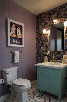 a bathroom with a toilet, sink and mirror in it's center wall color is purple