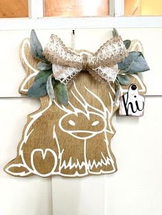 a door hanger with a wooden deer head and bow on it's side