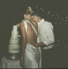 a man and woman standing next to each other near a cake