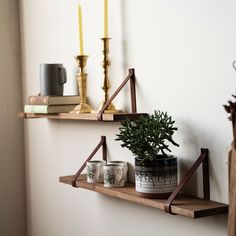 two wooden shelves with candles and plants on them