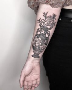 a woman's arm with flowers in a vase tattoo on her left forearm and right hand