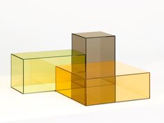 three different colored boxes sitting next to each other on a white surface with no one around them