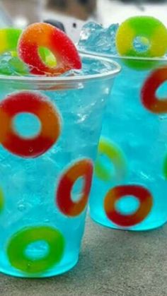 two cups filled with liquid and colorful circles on top of each other, sitting on a table