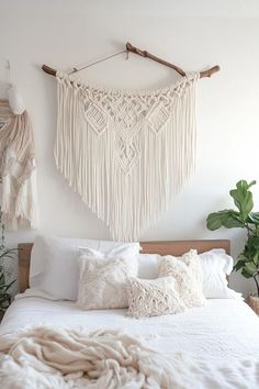 a white bed topped with lots of pillows next to a wooden headboard and wall hanging