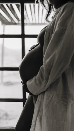 a pregnant woman standing in front of a window