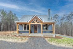 a small blue cabin sits in the middle of a wooded area