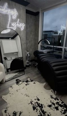 a black and white room with a large mirror, couch, chair and rug on the floor