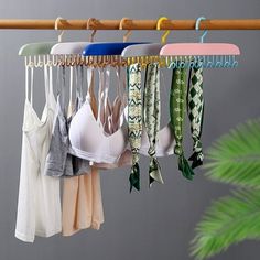 there are many different bras hanging on the clothes rack in front of a potted plant