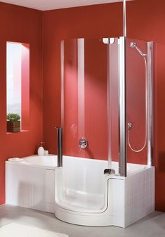 a bathroom with red walls and a white bathtub next to a window in the corner