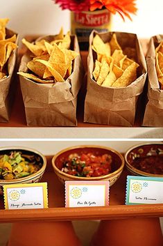 the table is full of chips, salsa and other condiments for a party