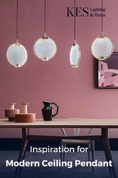 a dining room with pink walls and wooden table surrounded by hanging pendants above it