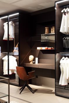 a room with some clothes on shelves and a chair in front of the closet door