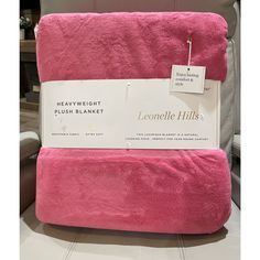 the pink blanket is on display for sale at the furniture store, and it has a price tag that says heavy weight plush blanket