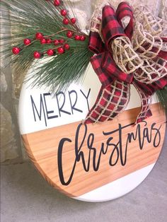 a wooden sign that says merry christmas with pine branches and red berries on the front