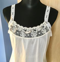 "This white nylon slip by Greenco Maid has lace straps and neckline. There is also lace trim at the hem. The straps are elastic lace but not adjustable. It is a size 38 with these measurements: Bust: 38\" Waist: 36\" Hips: 46\" Shoulder to hem: 40\" Strap length: 6\" Our items are in good condition. Should there be undue wear, something missing or inoperable it will be noted in our text and there will be a photo highlighting such. We add new items regularly and appreciate you taking a look." Sheer Lace Camisole For Daywear, White Fitted Lace Camisole, Summer Lace Camisole With Contrast Lace, White Camisole With Contrast Lace For Summer, White Contrast Lace Camisole For Summer, White Lace Camisole With Spaghetti Straps, Stretch Lace Camisole With Straps, White Lace Camisole With Delicate Straps, Daywear Camisole With Contrast Lace And Spaghetti Straps