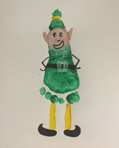 a drawing of a green elf with yellow feet and boots on it's legs