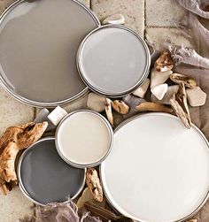 three paint cans sitting on top of a tile floor next to dried up driftwood