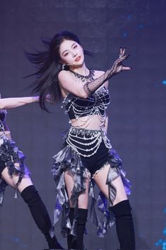 a woman in black and silver outfit on stage with her arms out to the side