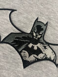 the batman logo is shown in black and white on a t - shirt that has been embroidered onto it