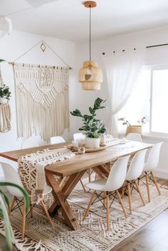 a dining room table with white chairs and plants