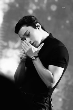 a black and white photo of a man with his hands folded over his face as he prays