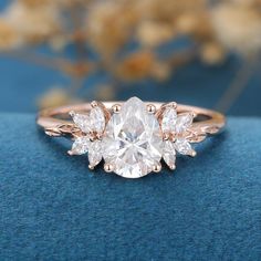 an oval cut diamond ring with three pear shaped diamonds on the band, set in 18k rose gold