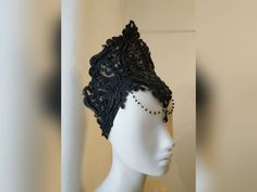 a white mannequin head with black lace and beads on it's face