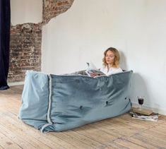 a woman sitting on top of a blue bean bag chair next to a glass of wine