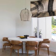 a dining room table with four chairs and a basket hanging from it's ceiling