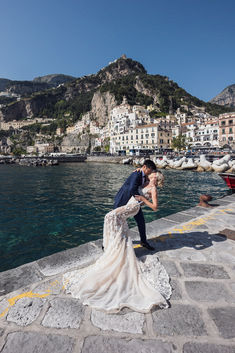 a bride and groom kissing in front of the water at their wedding venue, amalfa