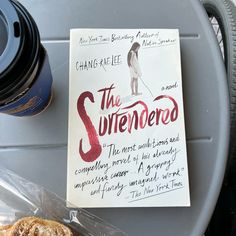 a book sitting on top of a metal tray next to a coffee cup and cookie